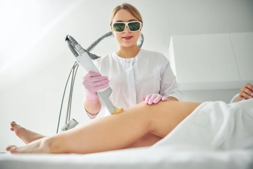 waxing vs laser hair removal, a person getting laser hair removal done on their leg